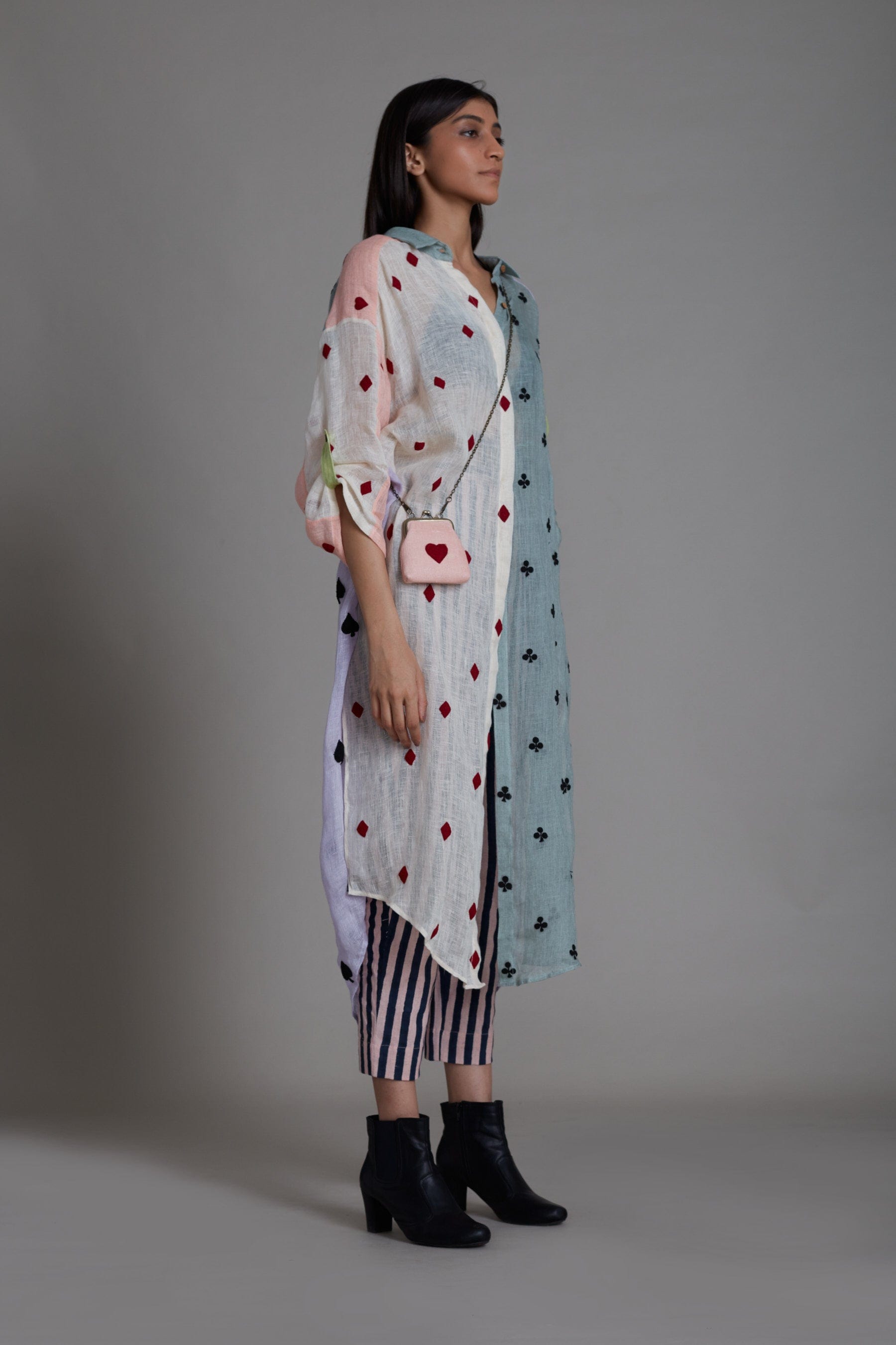 A female model wearing a Coord set, including a color block embroidered pure linen shirt with a V-neck and buttoned down detailing, paired with striped cotton pants that are elasticated at the back. Also includes a handwoven cotton black bralette.