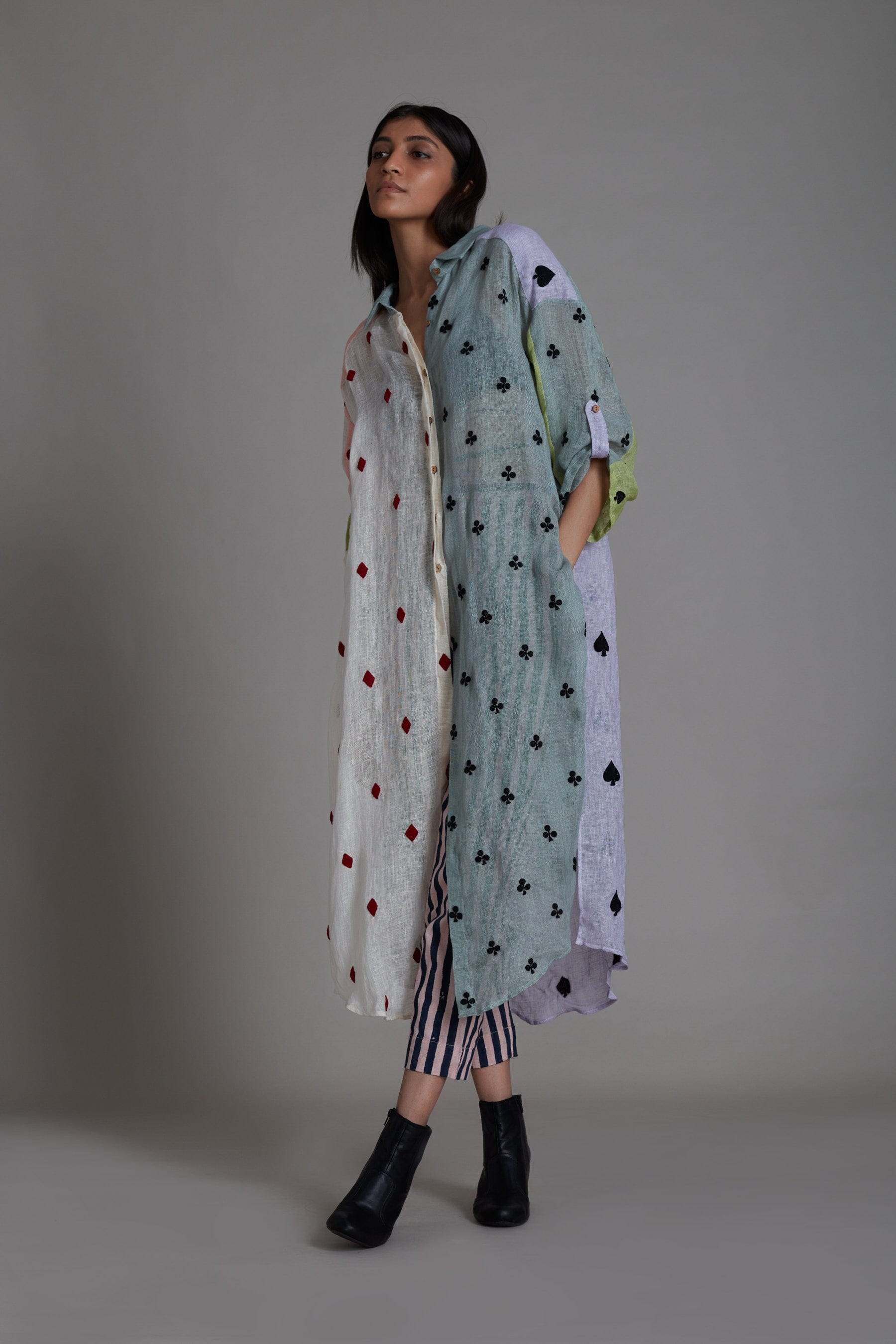 A female model wearing a Coord set, including a color block embroidered pure linen shirt with a V-neck and buttoned down detailing, paired with striped cotton pants that are elasticated at the back. Also includes a handwoven cotton black bralette.