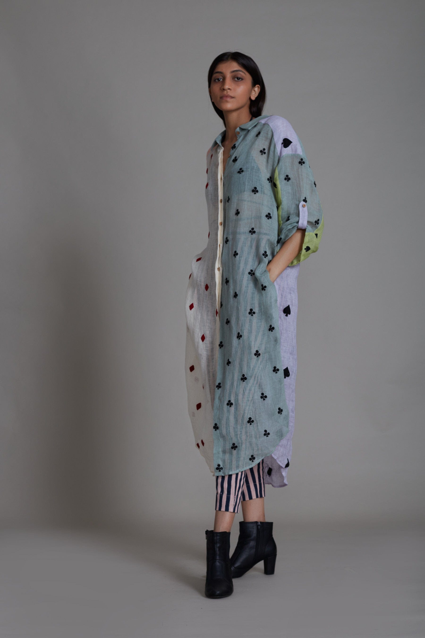 A female model wearing a Coord set, including a color block embroidered pure linen shirt with a V-neck and buttoned down detailing, paired with striped cotton pants that are elasticated at the back. Also includes a handwoven cotton black bralette.