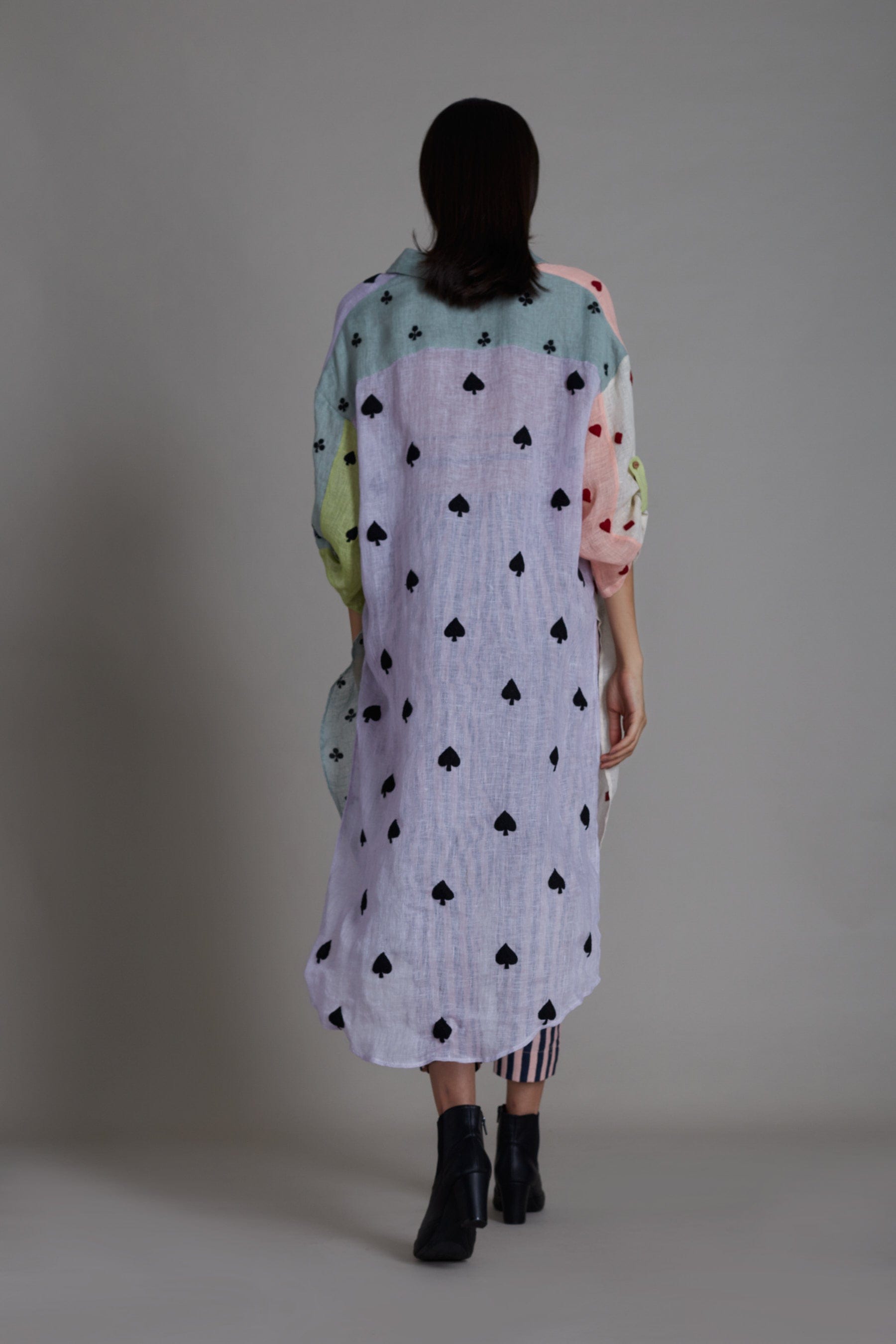 A female model wearing a Coord set, including a color block embroidered pure linen shirt with a V-neck and buttoned down detailing, paired with striped cotton pants that are elasticated at the back. Also includes a handwoven cotton black bralette.