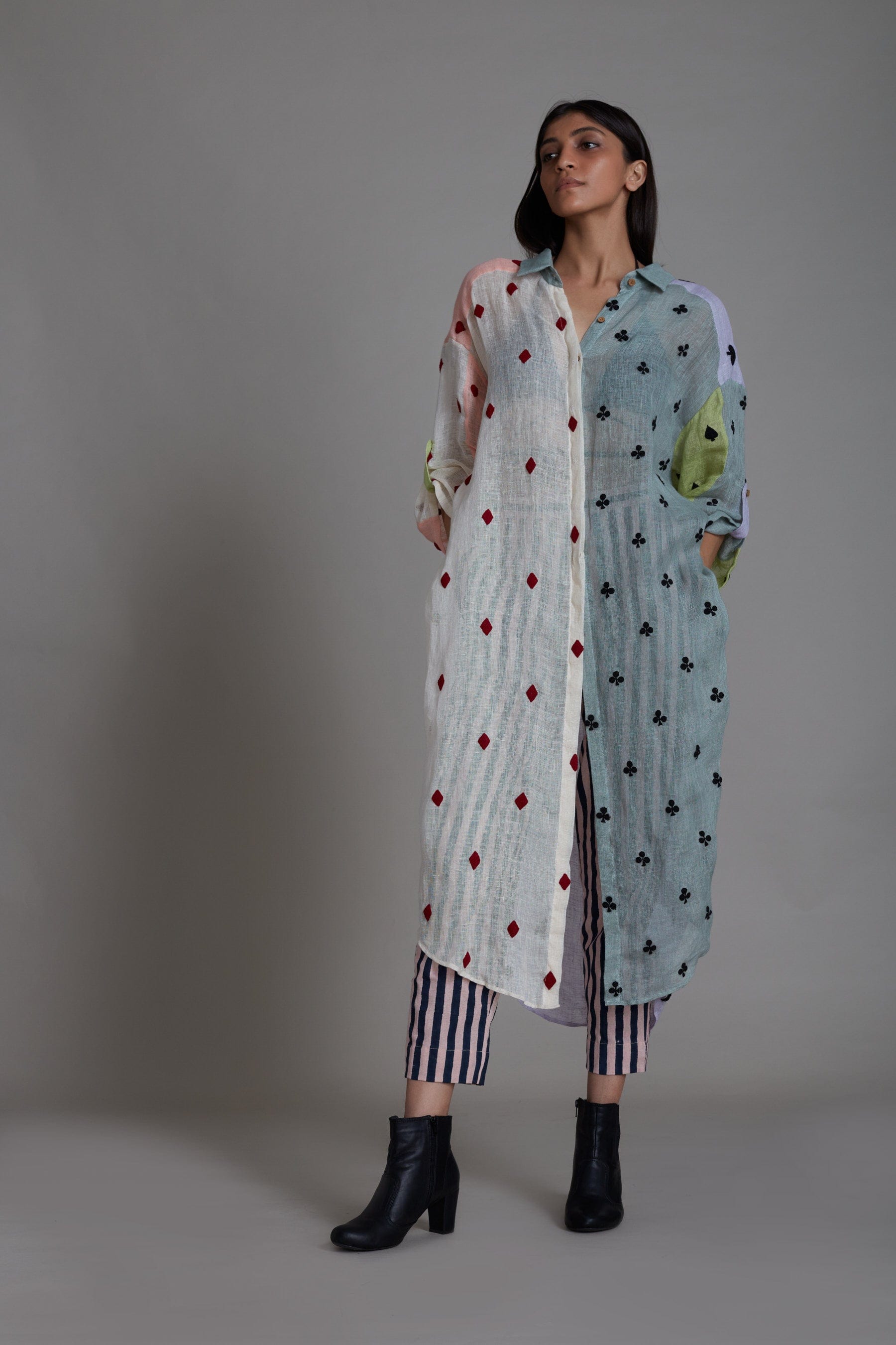 A female model wearing a Coord set, including a color block embroidered pure linen shirt with a V-neck and buttoned down detailing, paired with striped cotton pants that are elasticated at the back. Also includes a handwoven cotton black bralette.